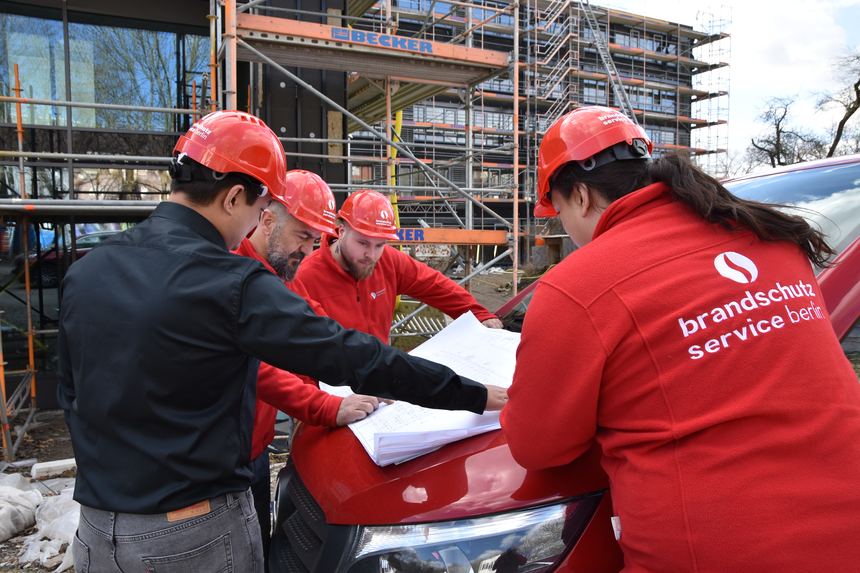 Team prüft Ausführungspläne vor dem Gebäude
